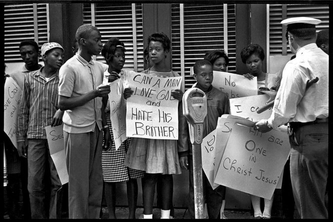 A police officer takes away protest signs on May 3, 1963. Moments later firemen hosed demonstrators. (Ed Jones/The Birmingham News)